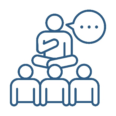 A person sitting in front of a group of people. The person has their legs cross and there is a speech bubble next to them.