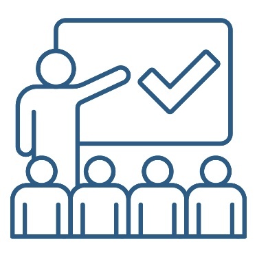 A person pointing at a whiteboard with a tick on it. In front of them is a group of people.