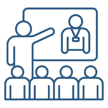 A person presenting to a group of people. They are pointing to a white board that shows a person wearing a nametag.