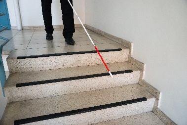 A person using a cane to walk down stairs.