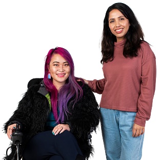 A person in a wheelchair and a person standing next to them with their hand on their shoulder.