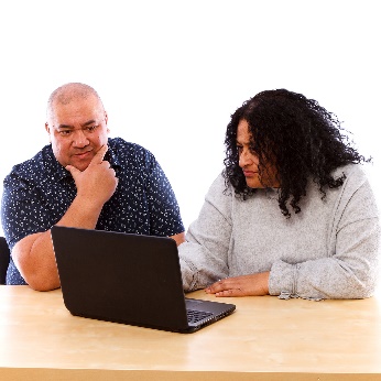 2 people using a latptop together.