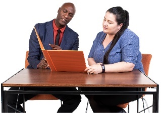 Two people sitting at a table looking at a folder together.