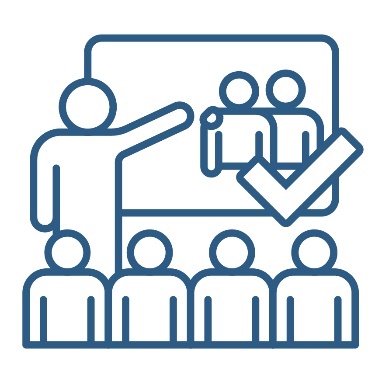A person giving a presentation to a group of people and a tick. They are pointing at a screen with positive behaviour support icon on it.